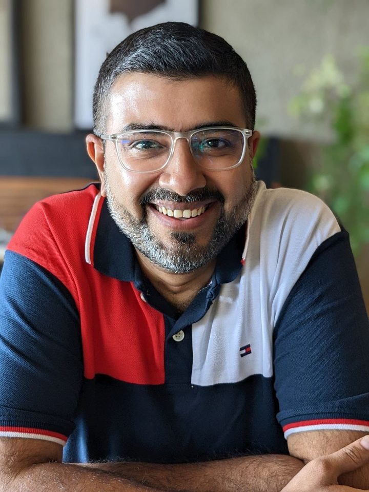 Mehul Fanawala, founder of NagMeLater, smiling in clear glasses and a red, white and navy polo shirt
